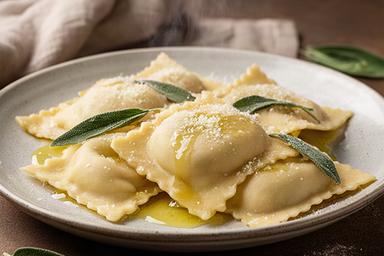 Ravioli ripieni fatti a mano con burro, salvia e formaggio grattugiato in cucina